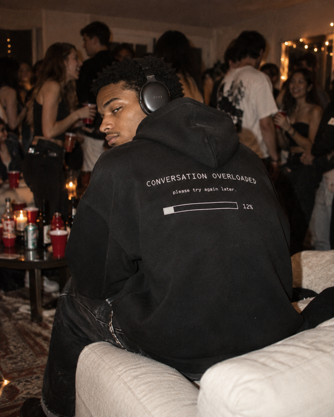 Man in Conversation Overloaded hoodie with headphones at a house party